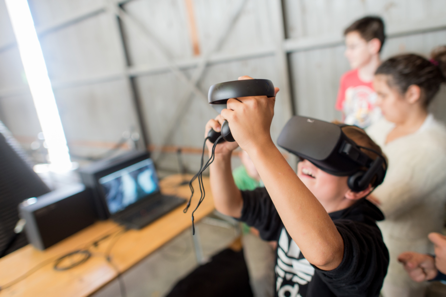 Junge trägt Virtuell Reality Brille und spielt mit Joystick